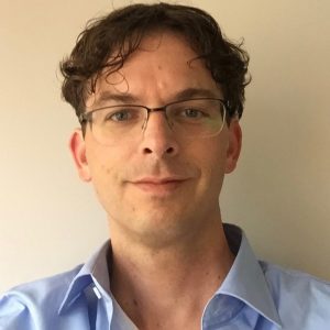 Foto van het gezicht van Jeroen Dudink met brol en lichtblauwe blouse